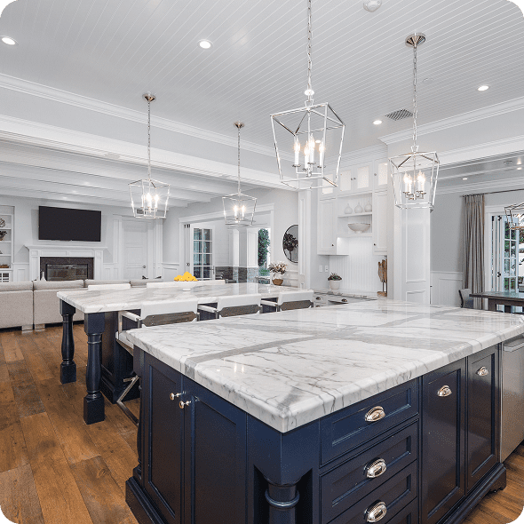 Modern kitchen with marble countertops and chandeliers.